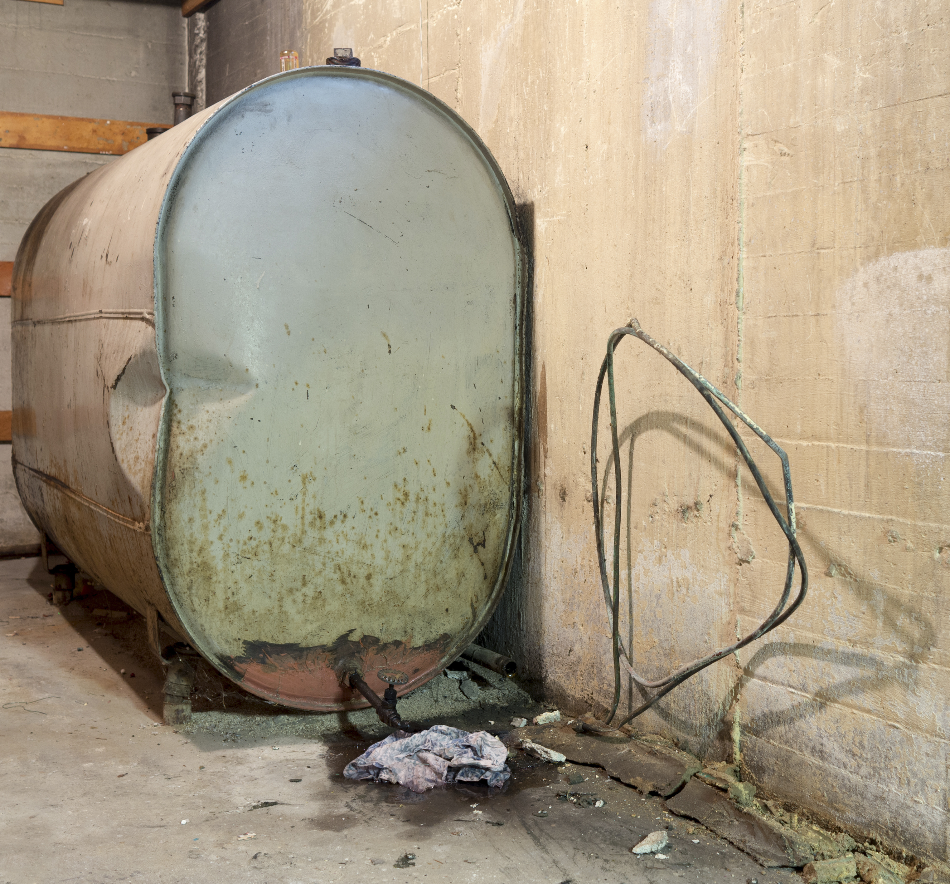 Old oil tank leaking oil in a basement